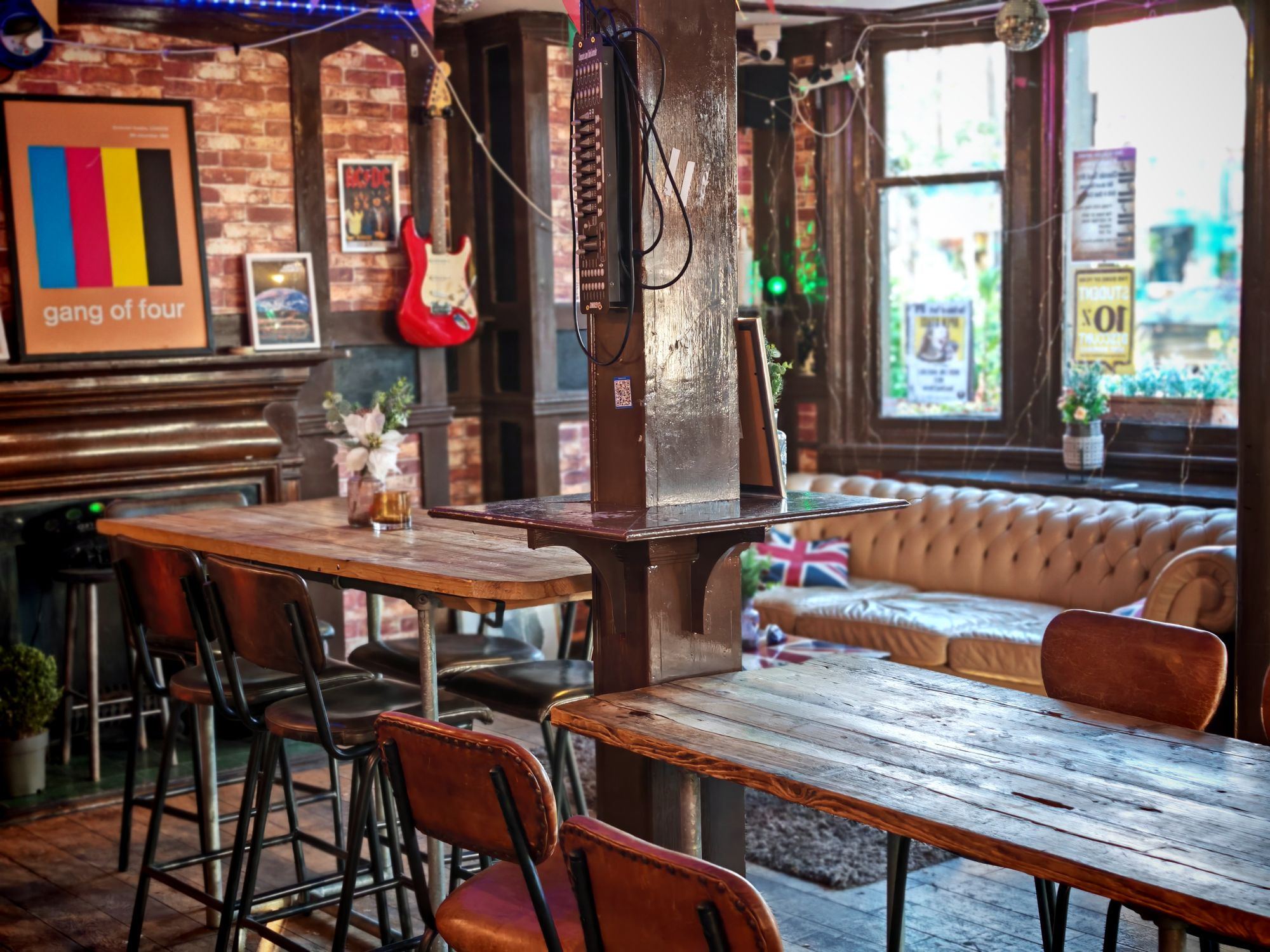 A cosy English pub interior with wooden tables, exposed brick and a Union flag sofa