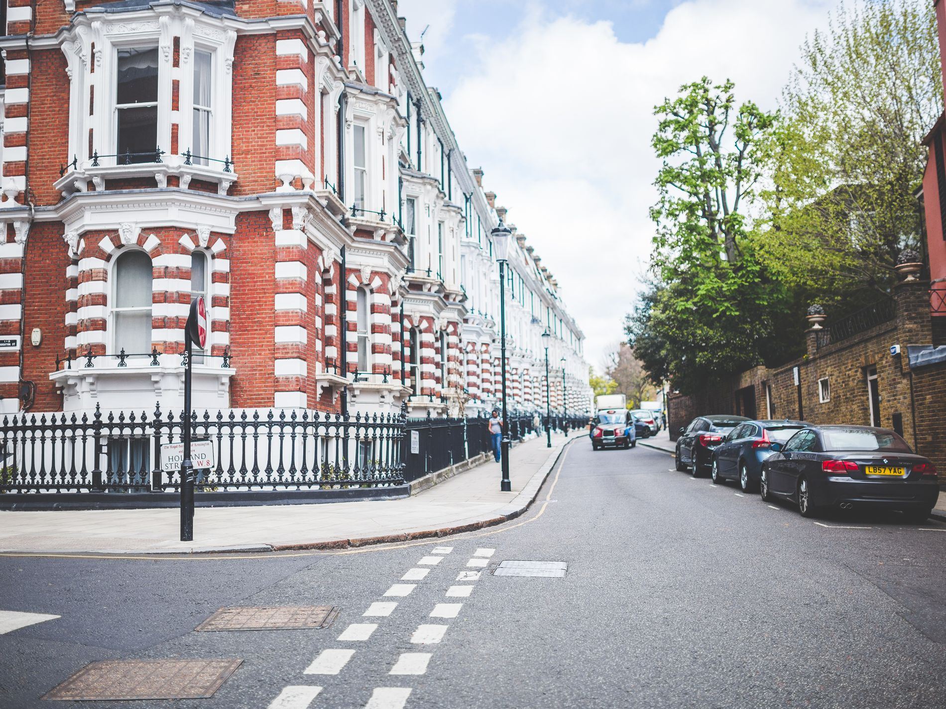 Victorian terraced buildings on a street corner with parked cars and trees.